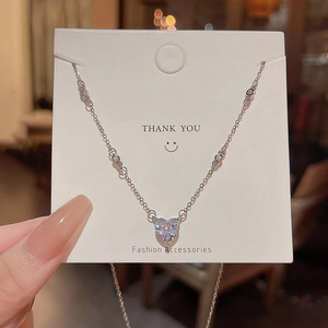 Detailed close-up of a silver heart pendant necklace featuring sparkling zircon stones