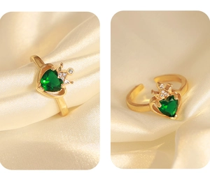 Dettaglio macro di un anello a corona d'oro con gemma verde a cuore su seta