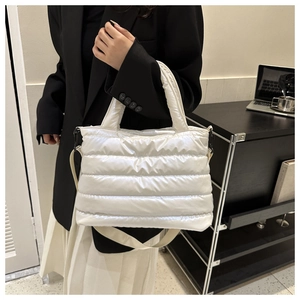 Borsa a mano bianca imbottita trapuntata con tracolla e manici su una scrivania