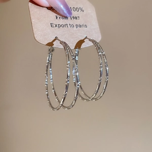 Close-up of silver-tone bamboo textured double layer hoop earrings on display card