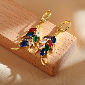Macro detail of gold leaf drop earrings with colorful marquise-cut stones on wood