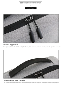 Detail of durable dual zippers and reinforced handle on the gray business laptop backpack