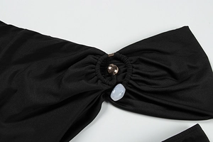 Detail of black knit dress featuring a gold ring with a blue marble pendant charm