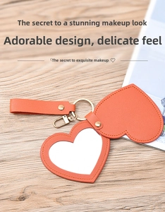 Macro detail of heart-shaped orange leather vanity mirror with gold keychain on wood