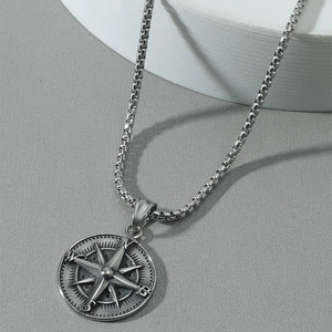 Close-up of a vintage compass pendant with star engraving on a silver box chain