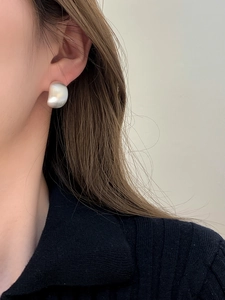 Macro shot of silver organic bean earrings with matte brushed finish on model