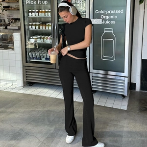 Dettaglio dei pantaloni a zampa a vita alta e crop top slim sul modello in un negozio