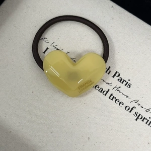 Macro detail of yellow heart resin hair tie with France Handmade text and black elastic