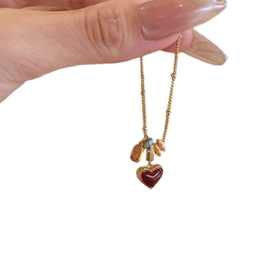 Elegant 18k gold plated necklace featuring a deep red heart pendant and delicate charms