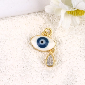 Detail of gold-plated evil eye pendant with blue iris and clear teardrop crystal