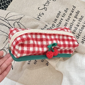 Detail of red and white plaid storage pouch with a small knitted cherry charm