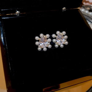 Macro view of 14k gold plated flower stud earrings with zircon and small white pearls