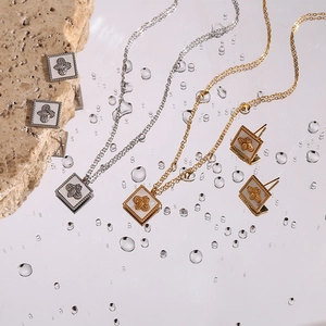 Macro shot of bee pendant necklace and earrings set on reflective mirror with water drops