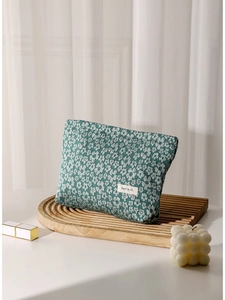 Floral canvas makeup bag with H&R logo tag on wooden stand with soft window lighting