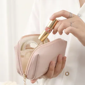 Portable light pink leather makeup bag with gold zipper shown in a hand-held use scene