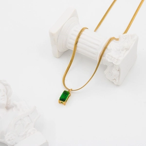 Elegant gold snake chain necklace with a rectangular green zircon pendant on white decor
