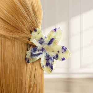 Floral hair claw clip with purple marble pattern worn on blonde hair in soft light