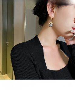 Detail of 12mm grey pearl drop earring with gold zircon setting on Asian model