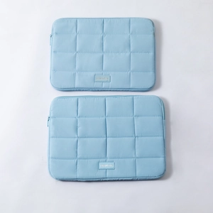 Detail of light blue quilted laptop and tablet sleeve set with zipper closure