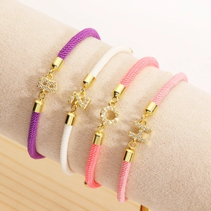 Detail view of colorful braided letter bracelets with gold-plated micro-pave charms