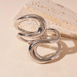 Dettaglio di un bracciale rigido a doppio cerchio in argento su pietra travertino