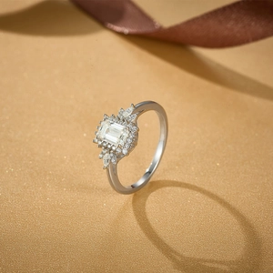 Macro view of emerald-cut moissanite silver ring on sparkling gold texture