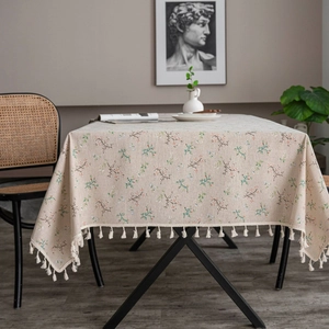 Detail of beige cotton linen tablecloth with floral patterns and fringe tassels