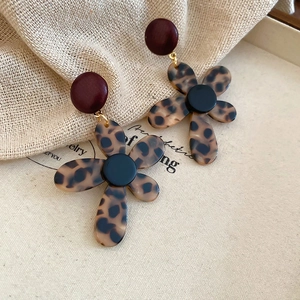 Close-up of retro leopard print flower earrings with red studs on rustic burlap backdrop