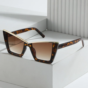 Fashionable cat-eye sunglasses with tortoise texture frame and gold trim on white podiums