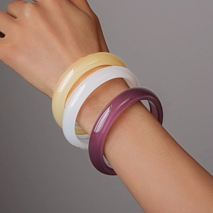 Three-piece geometric resin bangles in yellow, white, and purple on a model's wrist