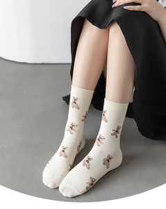 Close-up of cream cotton crew socks with repeated brown bear patterns and bow details