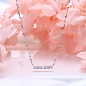 Detail shot of 925 silver necklace with rectangular zircon bar pendant on pink floral background