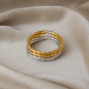 Detailed view of twisted rope textured hoop earrings in gold and silver on silk