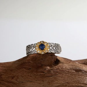 Macro shot of S925 silver ring featuring round blue gemstone in golden flower setting