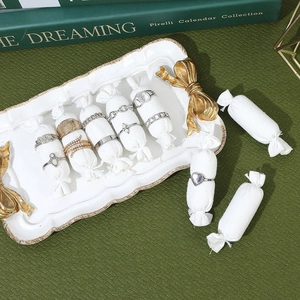 Linen ring display pillow with assorted gold and silver rings on white ceramic tray