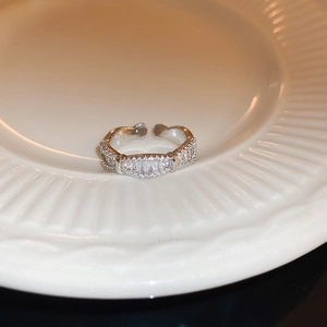 Gros plan d'une bague en argent avec zircons et perles sur une assiette en céramique blanche
