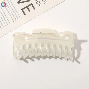 Macro shot of large pearlescent hair claw clip with iridescent finish and twisted design