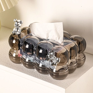 Detail of grey bubble tissue box with silver bear and bow on a white shelf