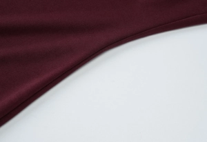 Gros plan du tissu tricoté bordeaux montrant la texture fine et les détails de couture