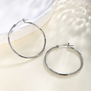 Detailed close-up of silver chain textured hoop earrings with secure clasp and light shadows