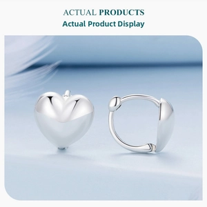 Close-up of polished 925 sterling silver heart-shaped earrings on a soft blue background