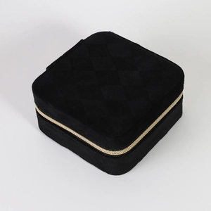 Close-up of quilted velvet jewelry box with gold zipper and textured black finish