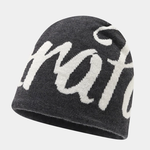 Close-up of the thick knit texture and jacquard lettering on the dark gray beanie