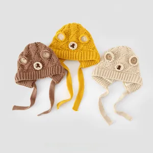 Detailed flat lay of knitted bear ear hats for kids in brown, yellow, and beige cotton