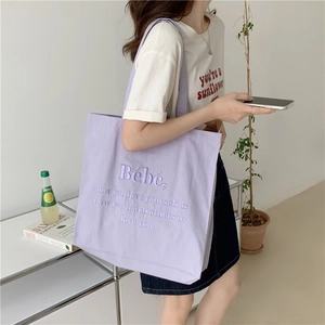 Detailansicht der lavendelfarbenen Canvas-Tasche mit Stickerei an einem Modell