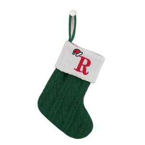 Detail of green knitted Christmas stocking with white cuff and red letter R embroidery