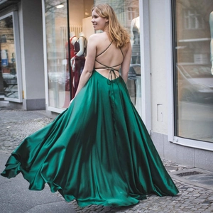 Elegant dark green satin evening gown featuring a deep backless design with cross straps