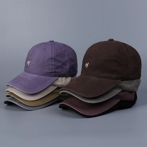 Close-up of washed cotton baseball caps with H embroidery in various vintage colors