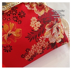 Détail macro d'un sac vintage rouge avec broderie dorée et fermoir en perles