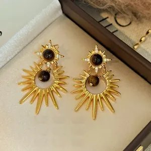 Detail of starburst earrings with brown tiger eye stone and zircons on champagne satin